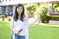 テニスラケットを持って微笑む女子大学生