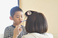 男の子の歯磨きを手伝う母親