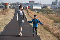 一緒に歩くスーツ姿の母親と小学生の男の子
