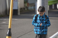 電信柱にもたれて下を向く小学生の男の子