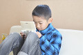 携帯ゲーム機で遊ぶ小学生の男の子