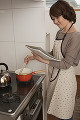キッチンでレシピを見ながら料理をする女性