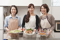 料理を載せた皿を持って見せる三人の女性