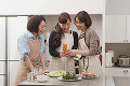 携帯電話で料理を撮影する三人の女性
