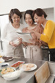 キッチンでレシピを見る三人の女性
