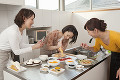 キッチンで菓子作りをする三人の女性