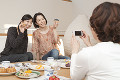 菓子を携帯電話で撮影をする三人の女性