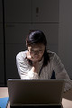 暗いオフィスでパソコンを見る若い女性