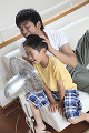 扇風機に顔を向けて遊ぶ父親と男の子