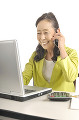 パソコンを操作しながら電話するシニア女性