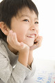 頬杖をついて笑顔を浮かべる男の子