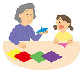 孫と折り紙をする老人女性