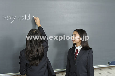黒板に文字を書く女子高校生二人