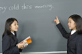 黒板の前に立つ女子高校生二人