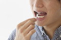 歯間ブラシを使う若い男性の口元
