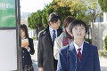 イヤホンを付けてバス停に立つ男子中学生