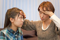 女子高校生の娘の熱を確認する母親