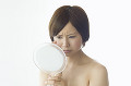 鏡を見て顔をしかめる日本人女性