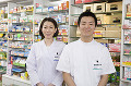 薬の商品棚の前に立つ薬剤師と登録販売者