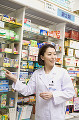 商品棚から薬を取り出す女性薬剤師