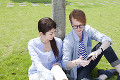 芝生に座り画面に触る留学生と大学生