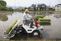 水田で田植機を運転する男性