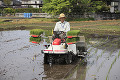 水田で田植機を運転する男性